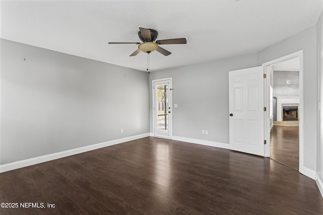 unfurnished room with dark hardwood / wood-style floors, ceiling fan, and a tiled fireplace