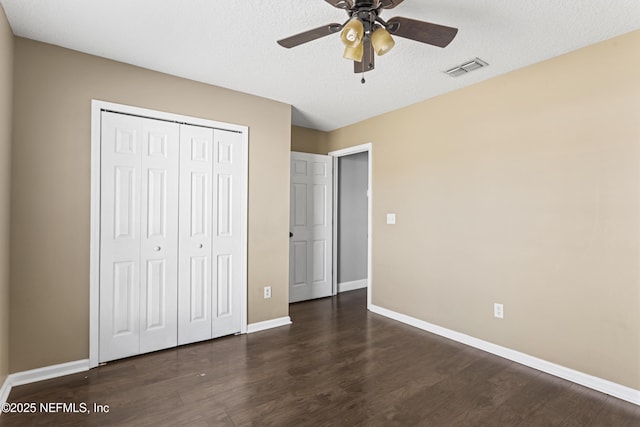 unfurnished bedroom with ceiling fan, dark hardwood / wood-style flooring, a textured ceiling, and a closet