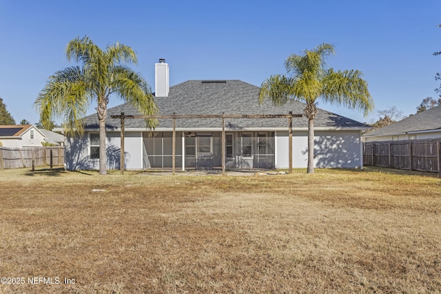 back of house featuring a lawn and a sunroom