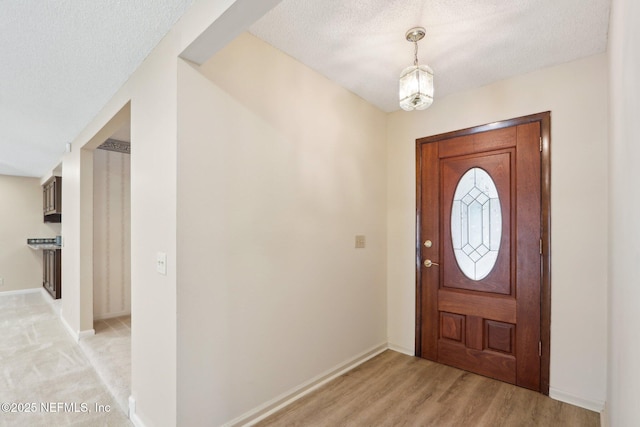 entryway with light hardwood / wood-style floors and a textured ceiling