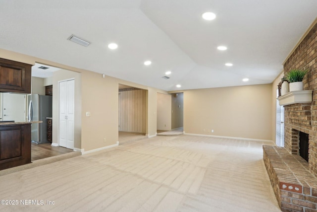 unfurnished living room featuring lofted ceiling, light carpet, and a fireplace