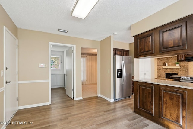 kitchen featuring decorative backsplash, stainless steel fridge with ice dispenser, light stone countertops, dark brown cabinets, and light hardwood / wood-style flooring