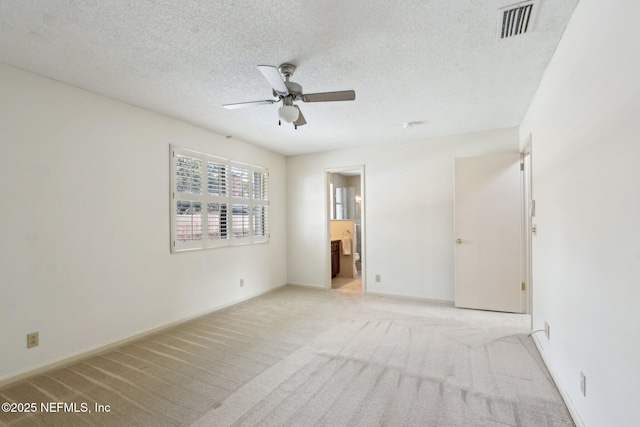 empty room with ceiling fan, light carpet, and a textured ceiling