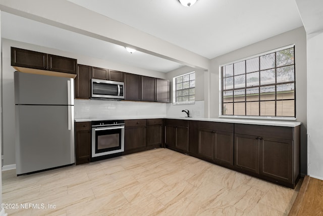 kitchen featuring tasteful backsplash, dark brown cabinetry, and appliances with stainless steel finishes