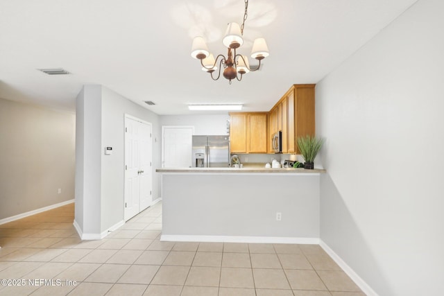 kitchen with decorative light fixtures, a chandelier, light tile patterned floors, appliances with stainless steel finishes, and kitchen peninsula