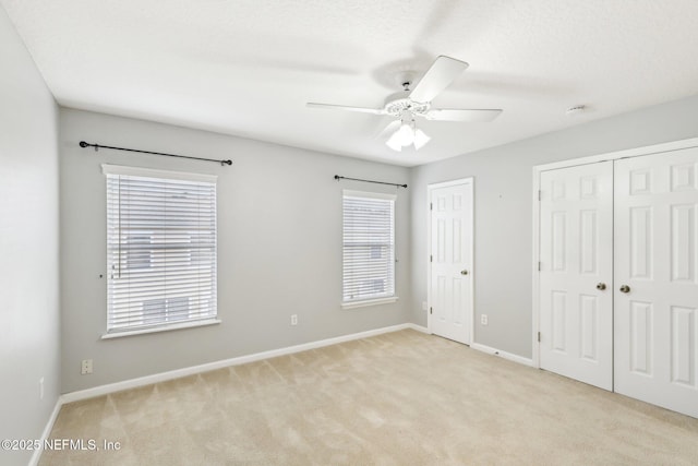 unfurnished bedroom with light carpet, two closets, and ceiling fan