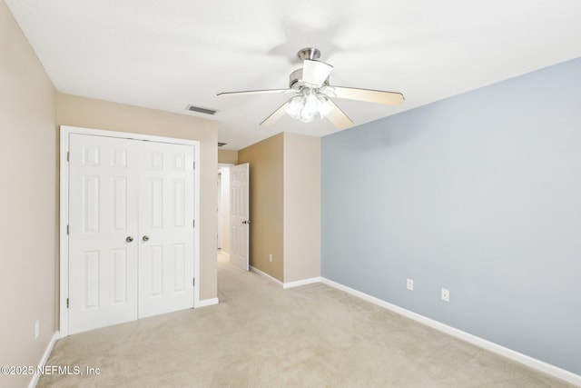 unfurnished bedroom featuring ceiling fan, a closet, and light carpet