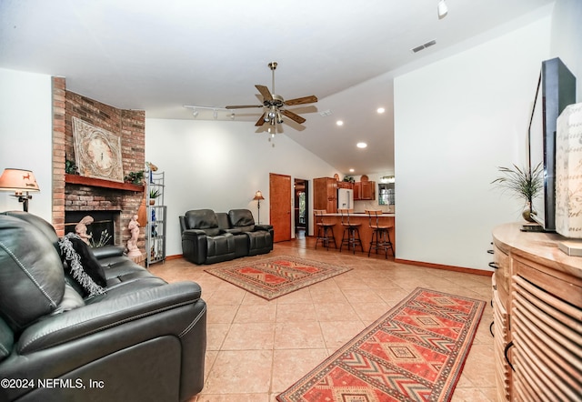 tiled living room with a brick fireplace, track lighting, vaulted ceiling, and ceiling fan