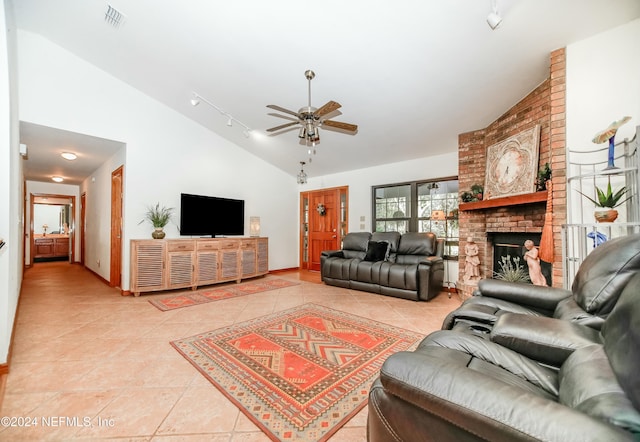 living room featuring rail lighting, a brick fireplace, ceiling fan, high vaulted ceiling, and light tile patterned flooring