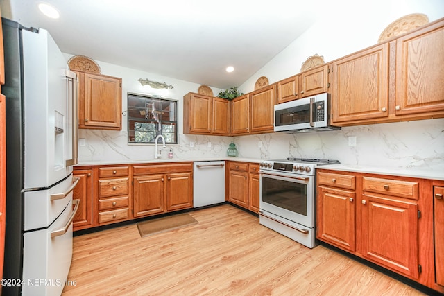 kitchen featuring backsplash, sink, stainless steel appliances, and light wood-type flooring