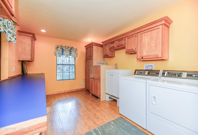 laundry area featuring washer and dryer, light hardwood / wood-style flooring, and cabinets