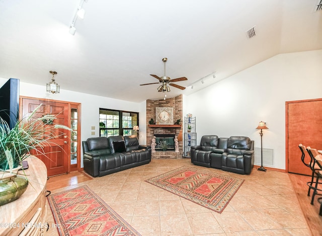 living room featuring track lighting, a brick fireplace, ceiling fan, light tile patterned floors, and lofted ceiling