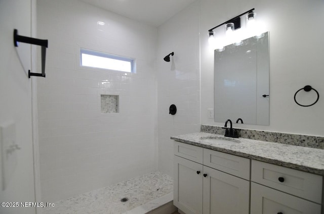 bathroom with tiled shower and vanity