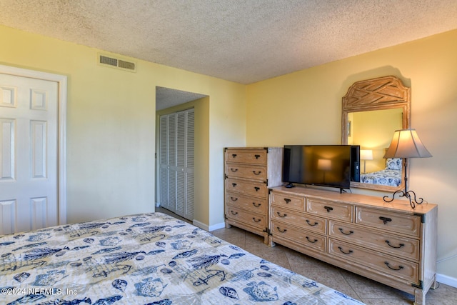 bedroom featuring light tile patterned floors, a textured ceiling, and a closet