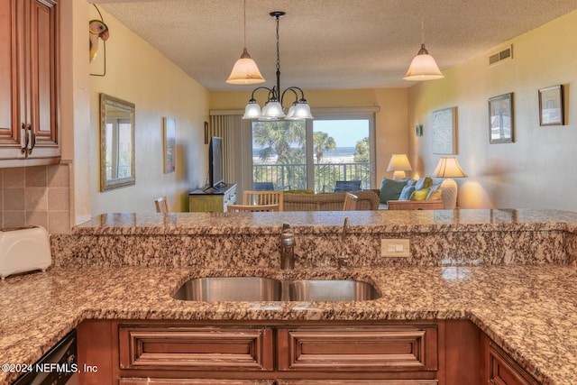 kitchen featuring a textured ceiling, decorative light fixtures, sink, and tasteful backsplash