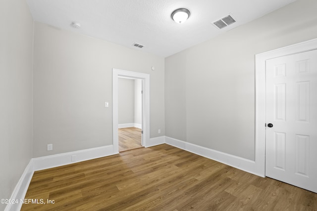 empty room with hardwood / wood-style floors and a textured ceiling