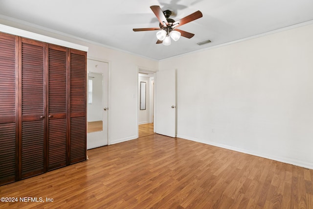 unfurnished bedroom with hardwood / wood-style floors, ceiling fan, ornamental molding, and a closet