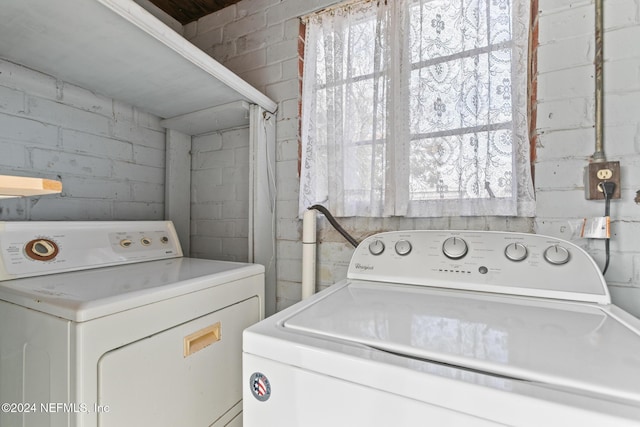 laundry area featuring washer and clothes dryer and brick wall