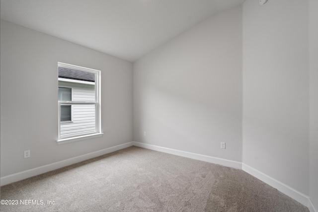 empty room with vaulted ceiling, carpet, and baseboards