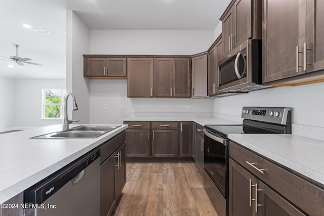 kitchen with light countertops, appliances with stainless steel finishes, a sink, and dark brown cabinetry