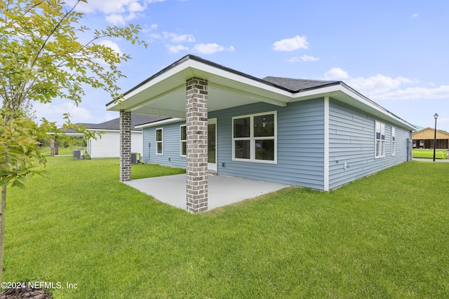 rear view of house with central AC, a patio, and a lawn