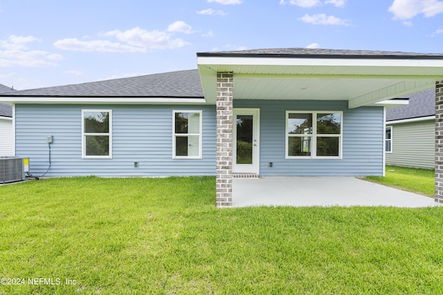 back of house featuring a shingled roof, cooling unit, a patio, and a lawn