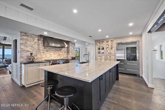 kitchen featuring a large island, wall chimney range hood, dark hardwood / wood-style floors, and sink