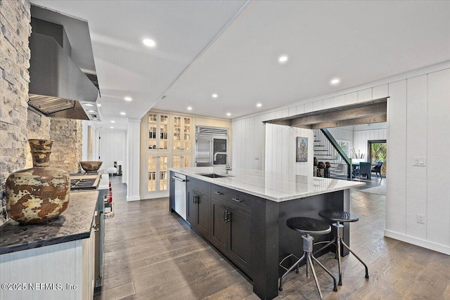 kitchen featuring appliances with stainless steel finishes, island range hood, wood-type flooring, a large island, and light stone countertops