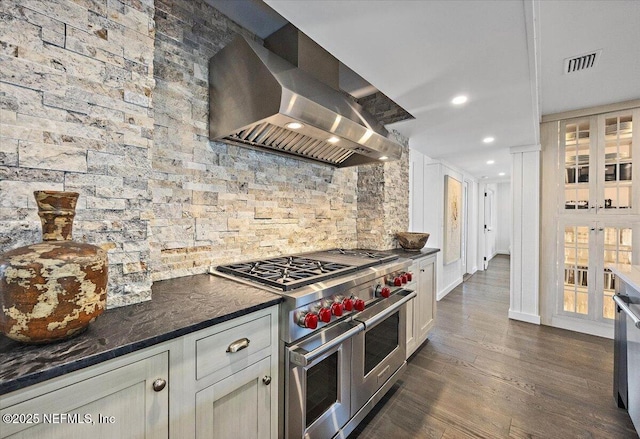 kitchen with white cabinetry, dark stone countertops, dark hardwood / wood-style floors, range with two ovens, and exhaust hood