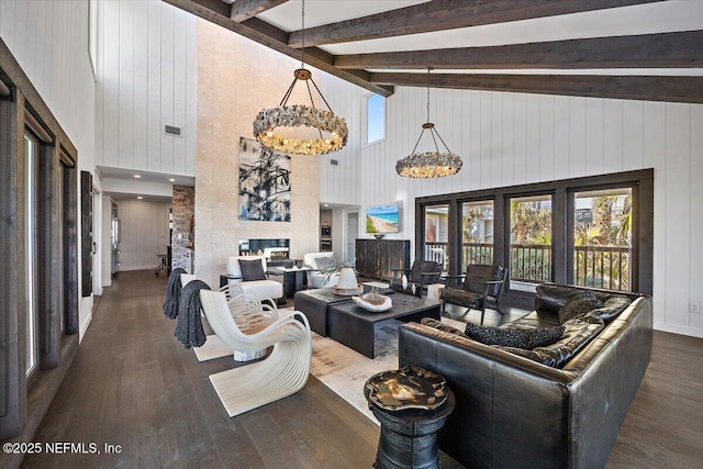 living room featuring an inviting chandelier, beam ceiling, high vaulted ceiling, a large fireplace, and dark hardwood / wood-style flooring