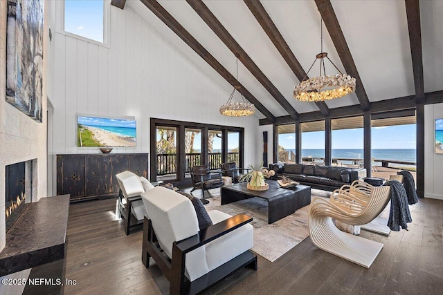 living room featuring a water view, high vaulted ceiling, an inviting chandelier, and a wealth of natural light