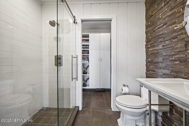 bathroom featuring toilet and a shower with shower door