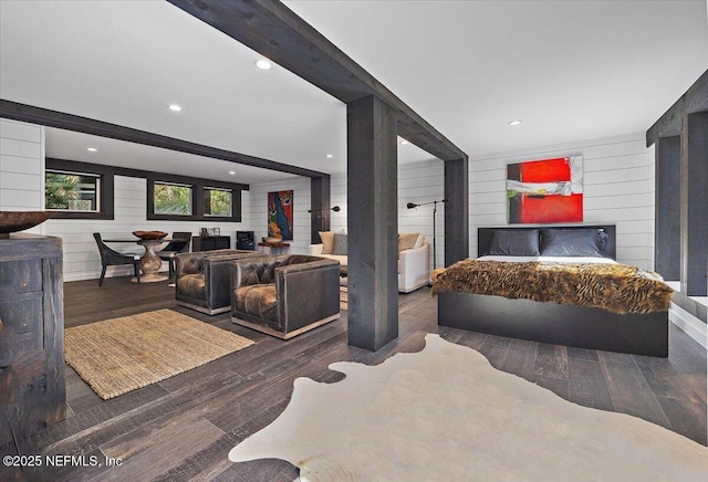 bedroom featuring dark hardwood / wood-style floors, a fireplace, beam ceiling, and wood walls