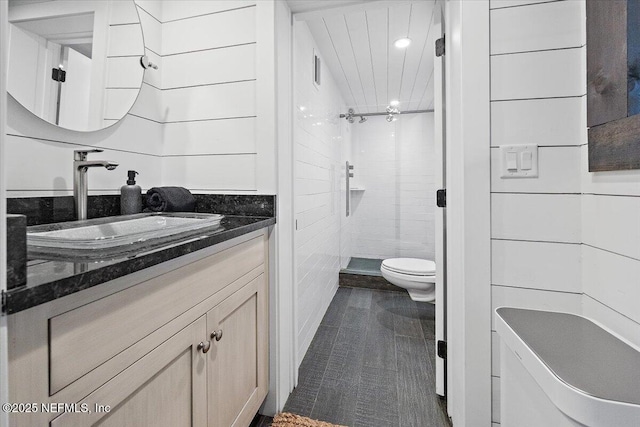 bathroom with vanity, tiled shower, and toilet