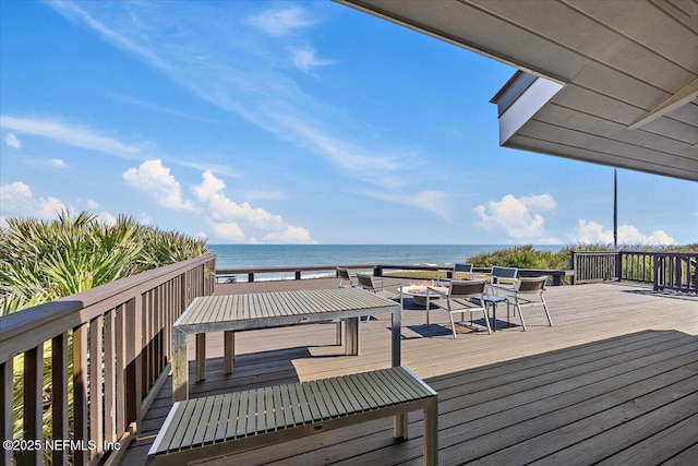 wooden deck with a water view and a fire pit