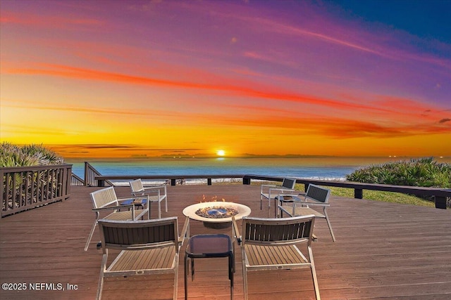 deck at dusk featuring a water view and a fire pit