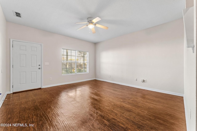 empty room with a textured ceiling, ceiling fan, and dark wood-type flooring