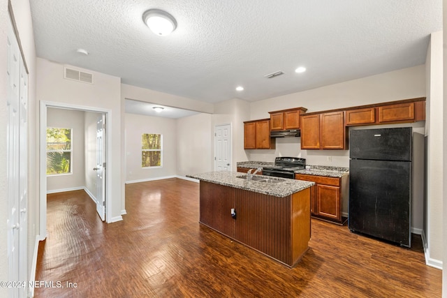 kitchen featuring light stone countertops, dark hardwood / wood-style floors, a textured ceiling, a kitchen island with sink, and black appliances