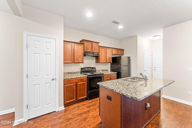 kitchen featuring dark wood-type flooring, sink, electric range, stainless steel refrigerator, and an island with sink