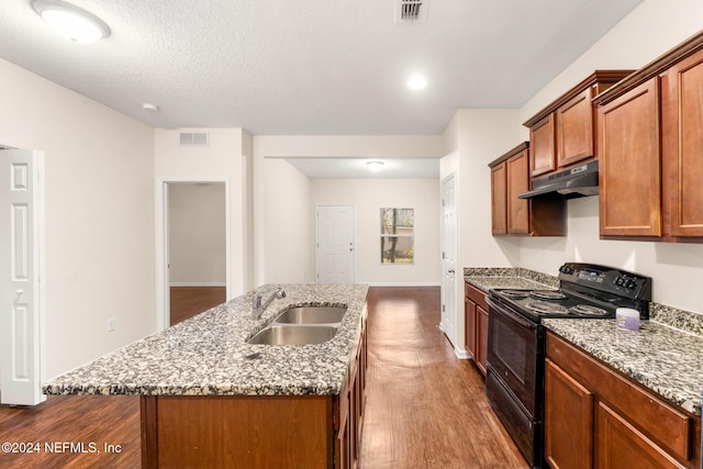 kitchen featuring a textured ceiling, sink, wood-type flooring, a center island with sink, and black / electric stove