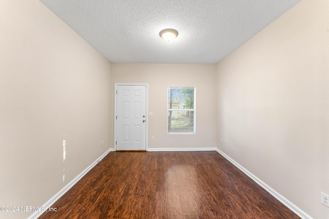 spare room featuring a textured ceiling and dark wood-type flooring