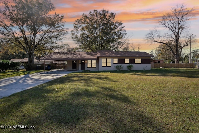 ranch-style house with a carport and a lawn