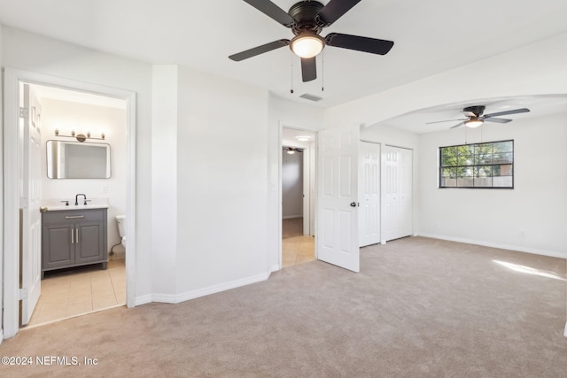 unfurnished bedroom featuring connected bathroom, ceiling fan, sink, and light carpet