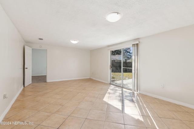 tiled empty room featuring a textured ceiling