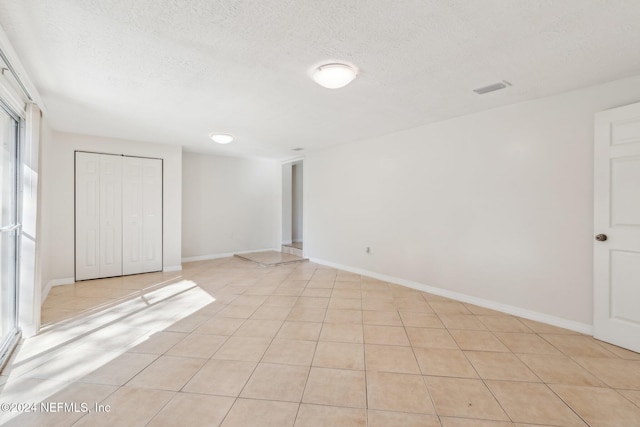 tiled empty room featuring a textured ceiling