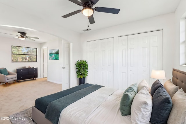 carpeted bedroom featuring two closets and ceiling fan