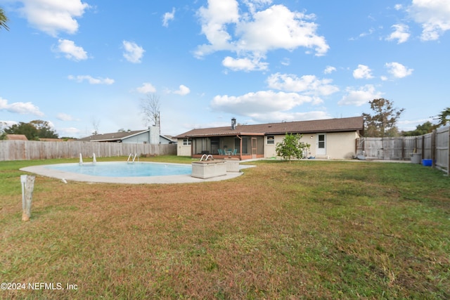 rear view of house featuring a lawn and a fenced in pool