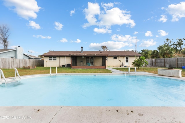 view of swimming pool featuring a yard and a sunroom