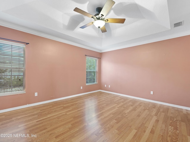 spare room with a raised ceiling, ceiling fan, ornamental molding, and light wood-type flooring