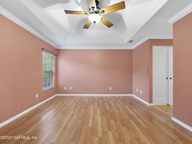 spare room with a tray ceiling, ornamental molding, and light hardwood / wood-style floors